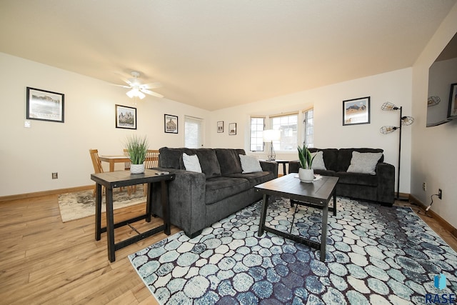 living room with a ceiling fan, light wood finished floors, and baseboards