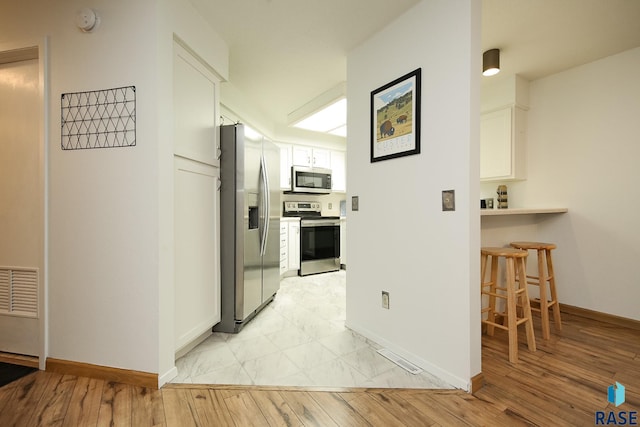 hall featuring baseboards and light wood-type flooring