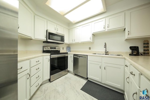 kitchen with stainless steel appliances, a sink, light marble finish flooring, white cabinets, and light countertops