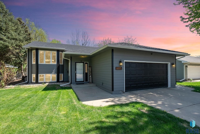 view of front facade featuring a garage, concrete driveway, and a yard