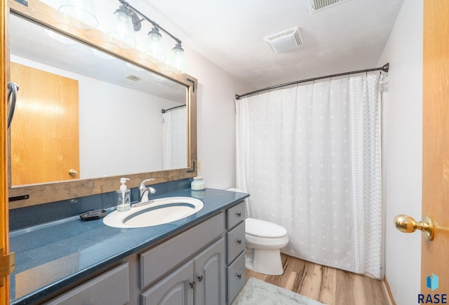 full bathroom with wood finished floors, toilet, vanity, and curtained shower