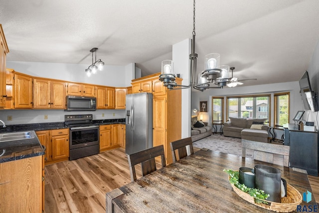 kitchen featuring appliances with stainless steel finishes, a sink, lofted ceiling, a chandelier, and open floor plan