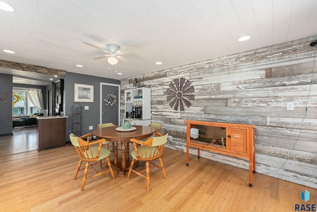dining area featuring an accent wall, a ceiling fan, wood finished floors, recessed lighting, and wood walls