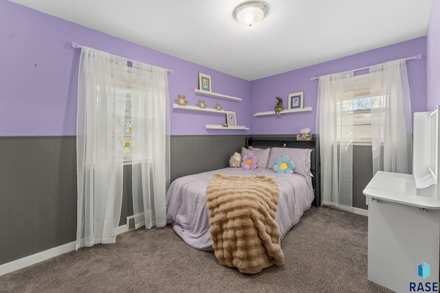 bedroom with carpet floors and wainscoting