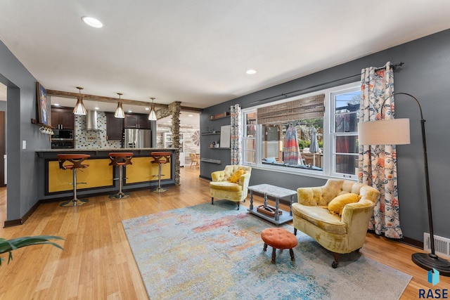 living area with ornate columns, wood finished floors, and recessed lighting