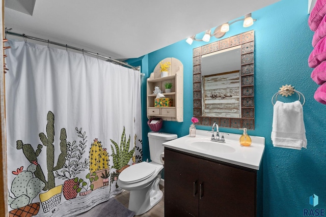 bathroom with vanity, toilet, a shower with shower curtain, wood finished floors, and a textured wall