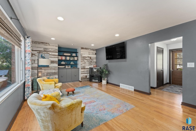 living room with plenty of natural light, baseboards, wood finished floors, recessed lighting, and built in shelves
