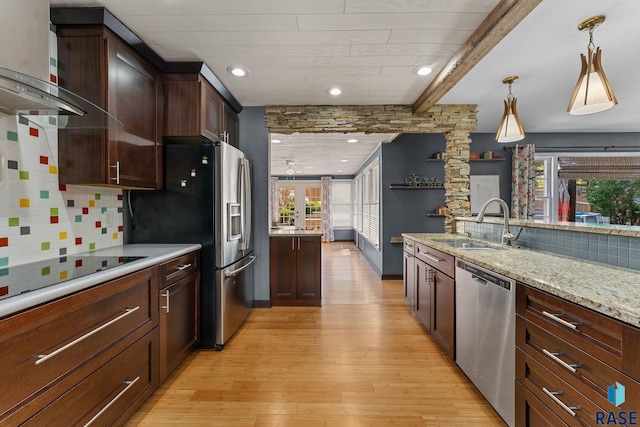 kitchen with stainless steel appliances, wall chimney range hood, a sink, plenty of natural light, and beamed ceiling