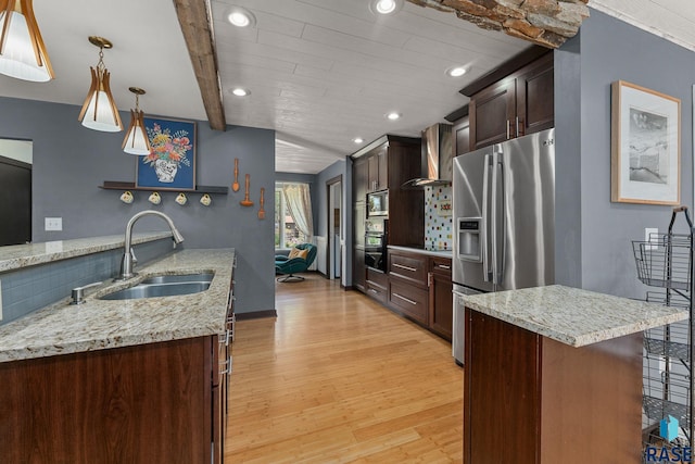 kitchen with stainless steel appliances, wall chimney range hood, a sink, light wood finished floors, and recessed lighting