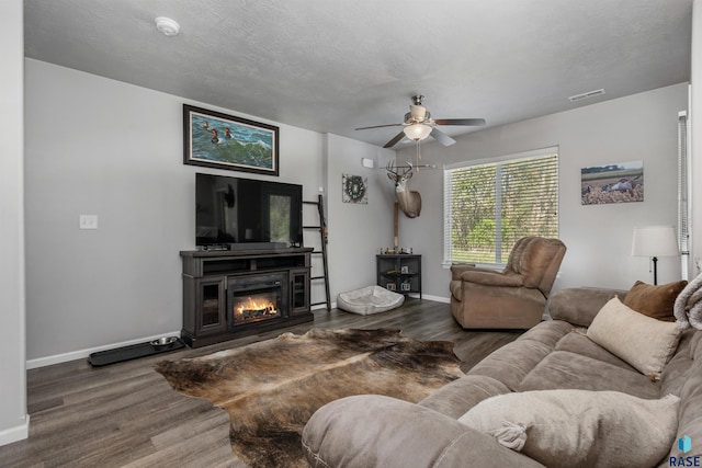 living room featuring wood finished floors, ceiling fan, baseboards, and a glass covered fireplace