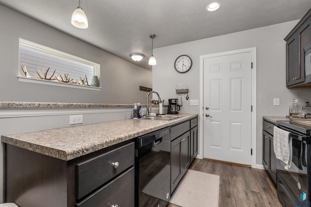 kitchen with black appliances, a sink, dark wood-style floors, decorative light fixtures, and light countertops