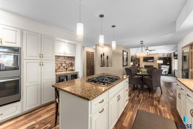 904 W Chicory Ln, Sioux Falls, SD 57108 - kitchen with black gas cooktop, double oven, a large fireplace, dark wood-style flooring, and light stone counters