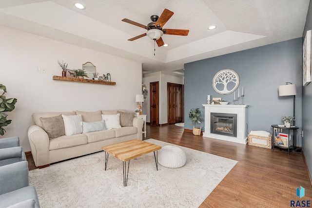 615 Marsha Cir, Tea, SD 57064 - living area featuring a tray ceiling, wood finished floors, ceiling fan, a glass covered fireplace, and recessed lighting