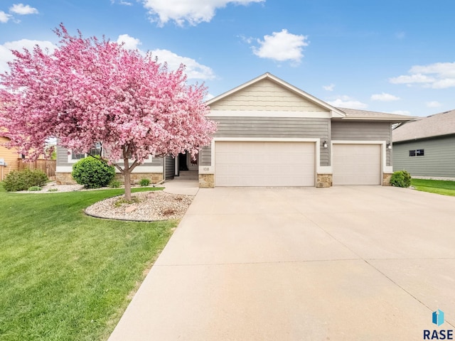 view of front of home with a garage, a front yard, driveway, and stone siding