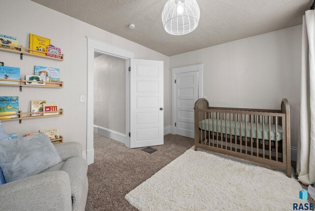 bedroom with carpet floors, a textured ceiling, a nursery area, baseboards, and vaulted ceiling