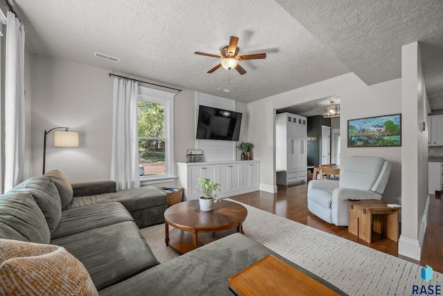living area with a textured ceiling, ceiling fan, wood finished floors, baseboards, and a chandelier