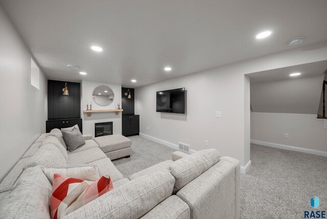 carpeted living area featuring baseboards, recessed lighting, and a glass covered fireplace