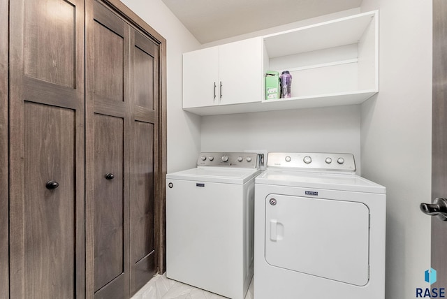 laundry room with washer and clothes dryer, cabinet space, and light marble finish flooring