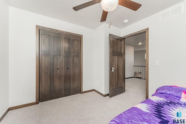 bedroom featuring light colored carpet, baseboards, a closet, and ceiling fan