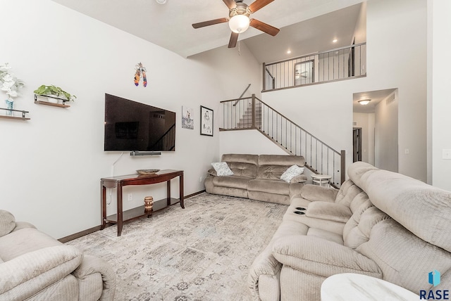 living room featuring stairs, ceiling fan, baseboards, and a high ceiling