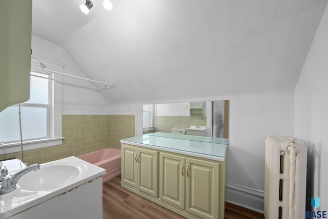 1420 W 10th St, Sioux Falls, SD 57104 - bathroom featuring radiator heating unit, lofted ceiling, plenty of natural light, wood finished floors, and a bathtub