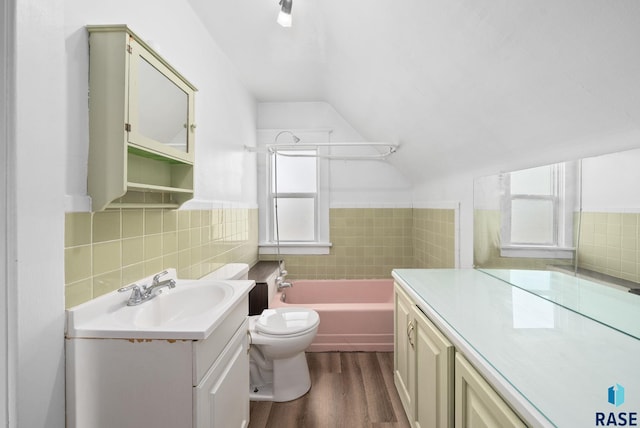 1420 W 10th St, Sioux Falls, SD 57104 - bathroom featuring vanity, tile walls, vaulted ceiling, wood finished floors, and toilet