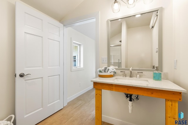28262 472nd Ave, Worthing, SD 57077 - bathroom featuring a sink, wood finished floors, vaulted ceiling, and baseboards