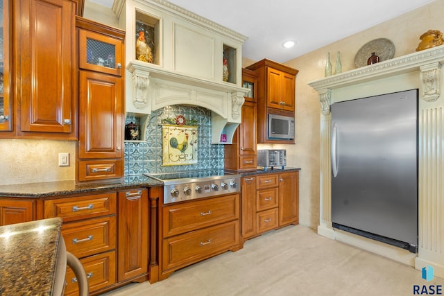 28262 472nd Ave, Worthing, SD 57077 - kitchen featuring appliances with stainless steel finishes, backsplash, glass insert cabinets, brown cabinetry, and dark stone countertops