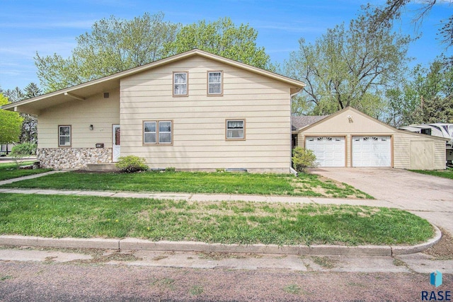 view of front facade featuring driveway, a garage, a front yard, and an outbuilding