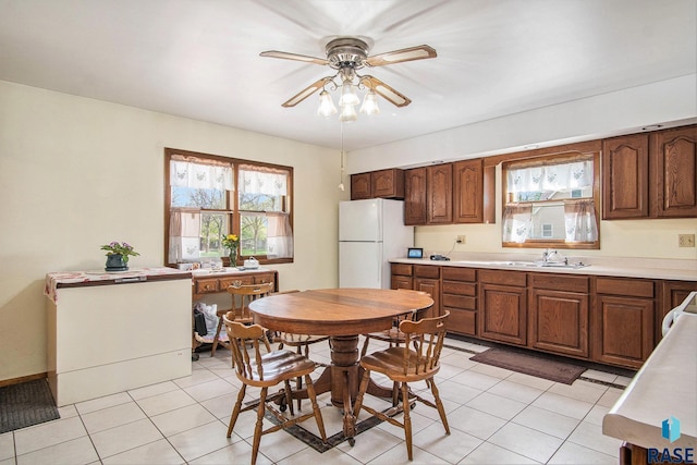 kitchen with freestanding refrigerator, a sink, ceiling fan, and light tile patterned floors
