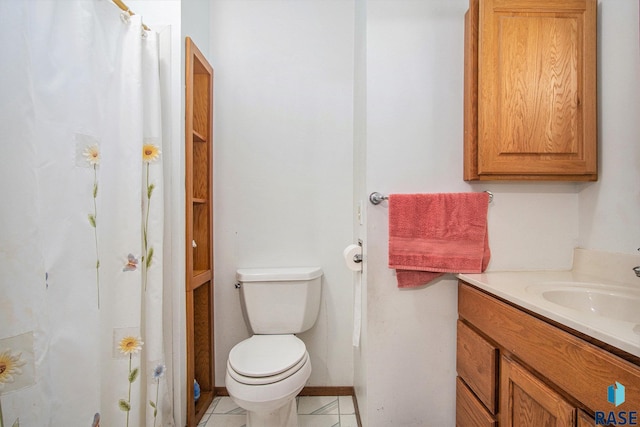 bathroom featuring toilet, vanity, baseboards, and tile patterned floors