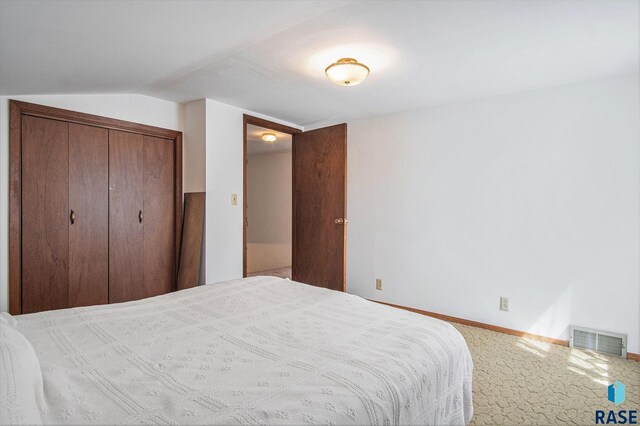 bedroom with lofted ceiling, baseboards, carpet floors, and a closet