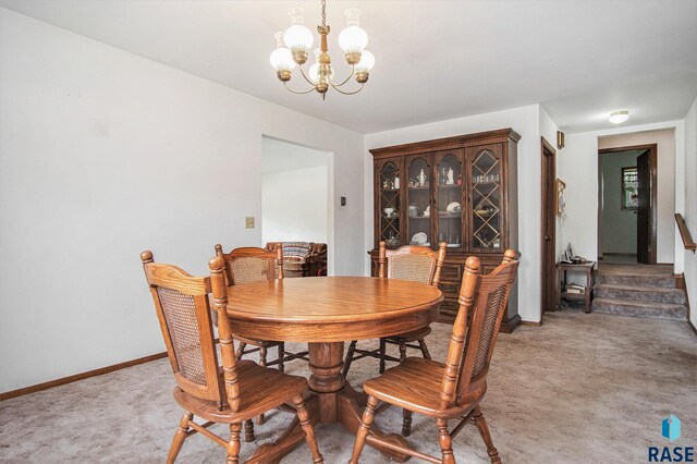 dining room featuring a chandelier, light carpet, and baseboards