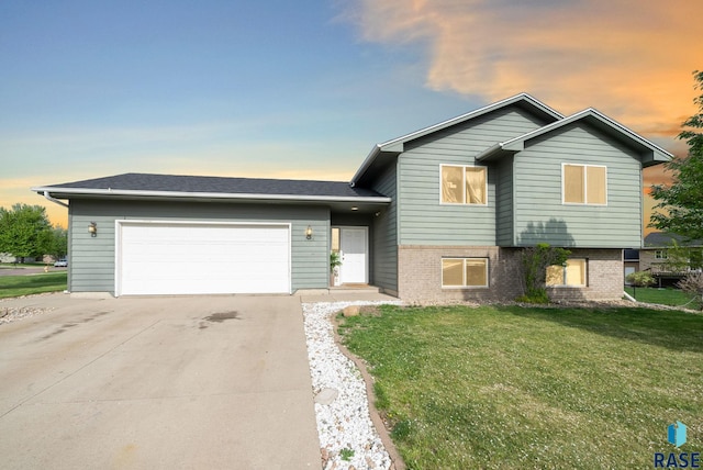 tri-level home with an attached garage, a lawn, concrete driveway, and brick siding