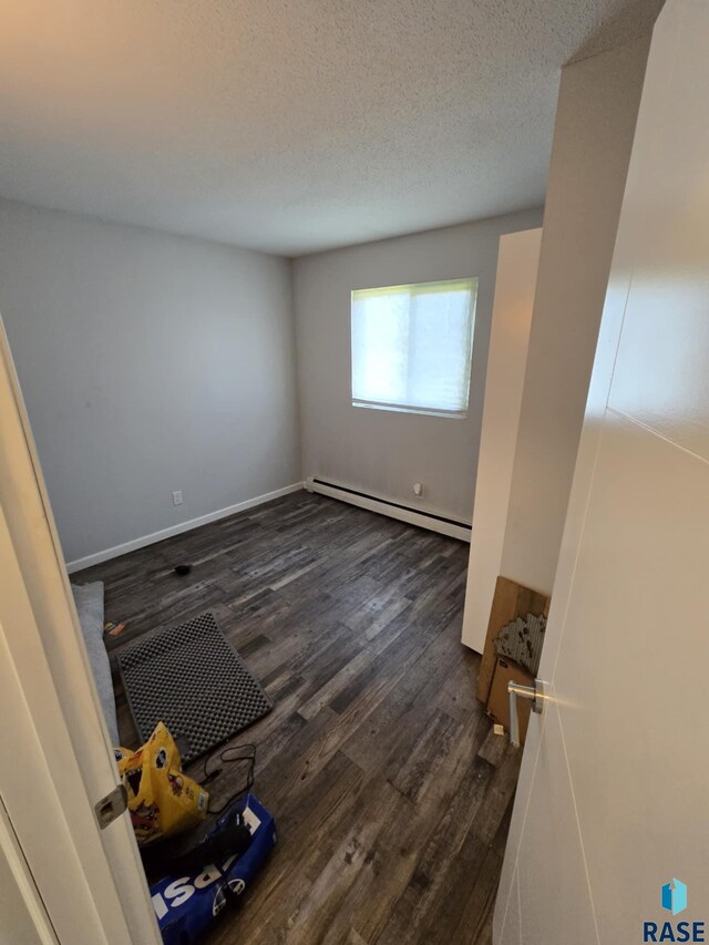 310 Jackson St, Valley Springs, SD 57068 - unfurnished room with a baseboard radiator, dark wood-style floors, and a textured ceiling