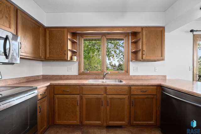 kitchen with appliances with stainless steel finishes, open shelves, a sink, brown cabinets, and light countertops