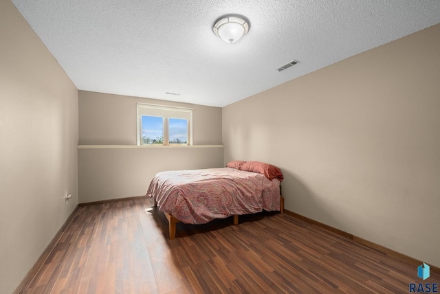 bedroom featuring wood finished floors, a textured ceiling, and baseboards
