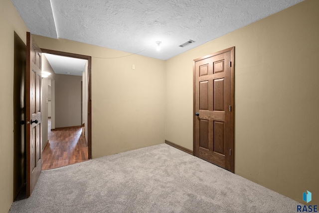 carpeted empty room with a textured ceiling
