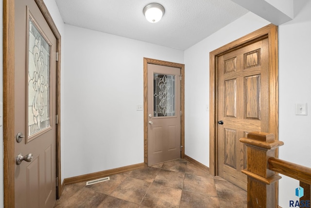 foyer featuring baseboards and a textured ceiling