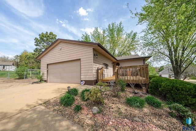 ranch-style house featuring a wooden deck, concrete driveway, and fence