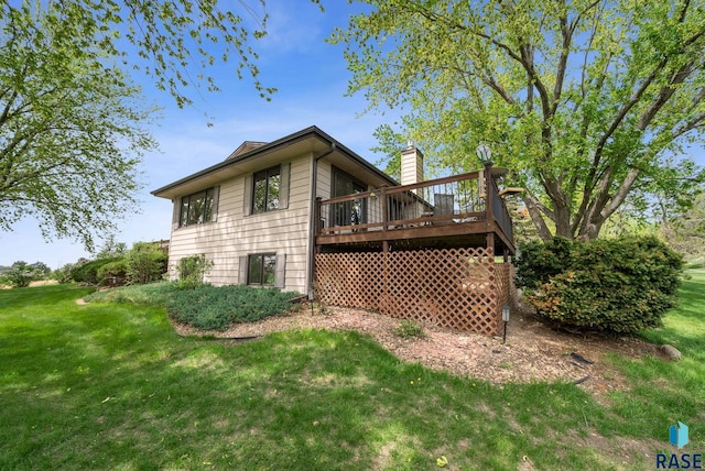 rear view of house featuring a wooden deck, a yard, and a chimney