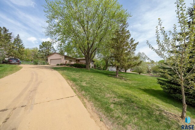view of front facade with dirt driveway, a front yard, and an attached garage