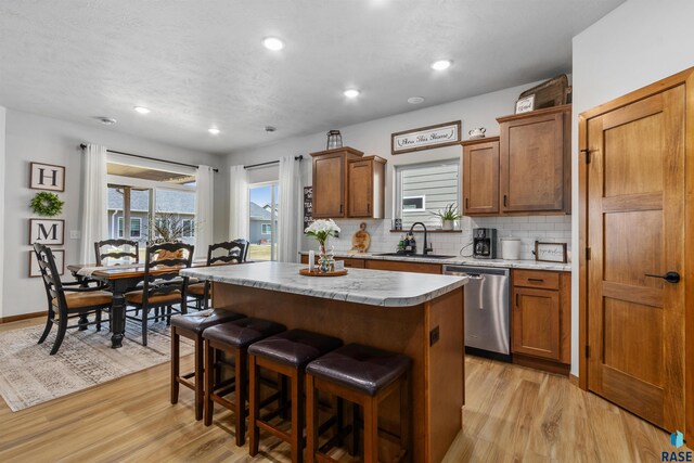 5307 S Dubuque Ave, Sioux Falls, SD 57108 - kitchen featuring dishwasher, a sink, a center island, brown cabinetry, and light wood-style flooring