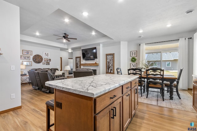5307 S Dubuque Ave, Sioux Falls, SD 57108 - kitchen featuring a ceiling fan, brown cabinets, light countertops, a kitchen island, and light wood-style floors