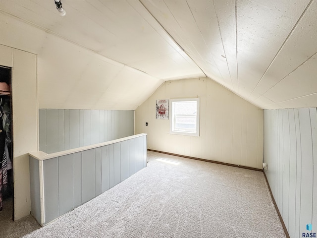 additional living space with carpet flooring, wood walls, and lofted ceiling
