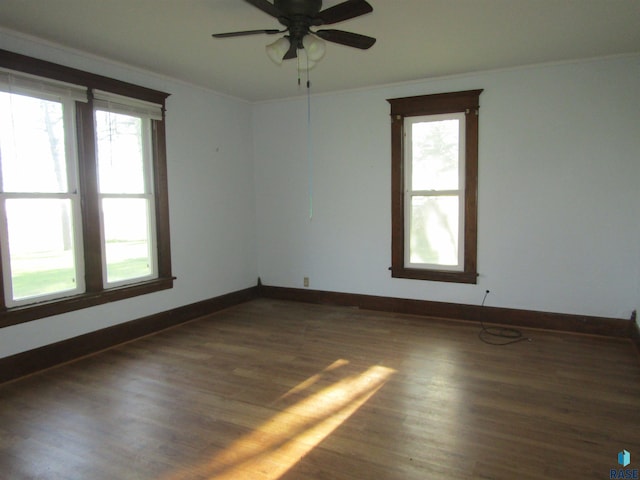 unfurnished room with plenty of natural light, ornamental molding, wood finished floors, a ceiling fan, and baseboards