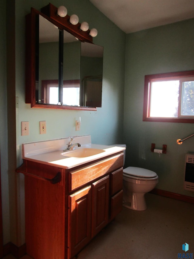 bathroom with heating unit, vanity, and toilet