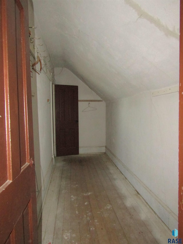 additional living space with vaulted ceiling, light wood-style flooring, and baseboards