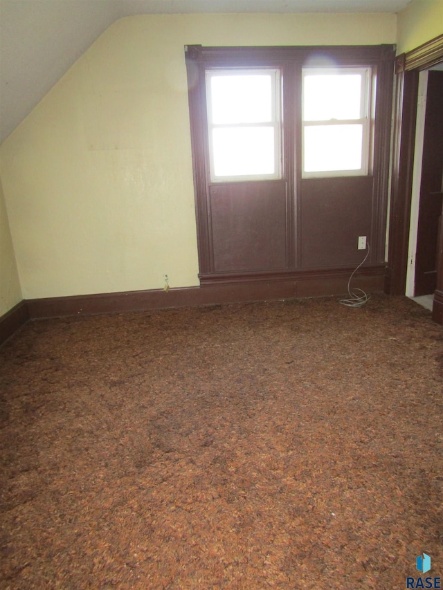 additional living space with carpet floors, vaulted ceiling, plenty of natural light, and baseboards