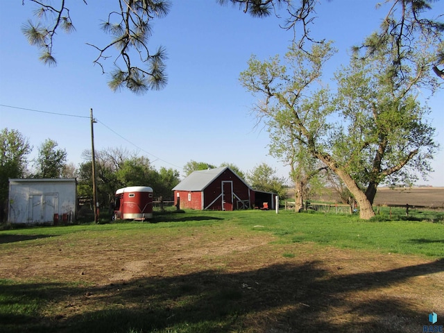 view of green lawn featuring a barn and an outbuilding